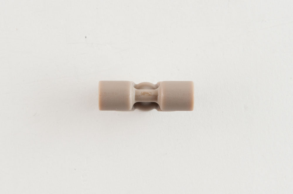 A compact plastic object with two openings, suggesting functionality for securing or linking components.