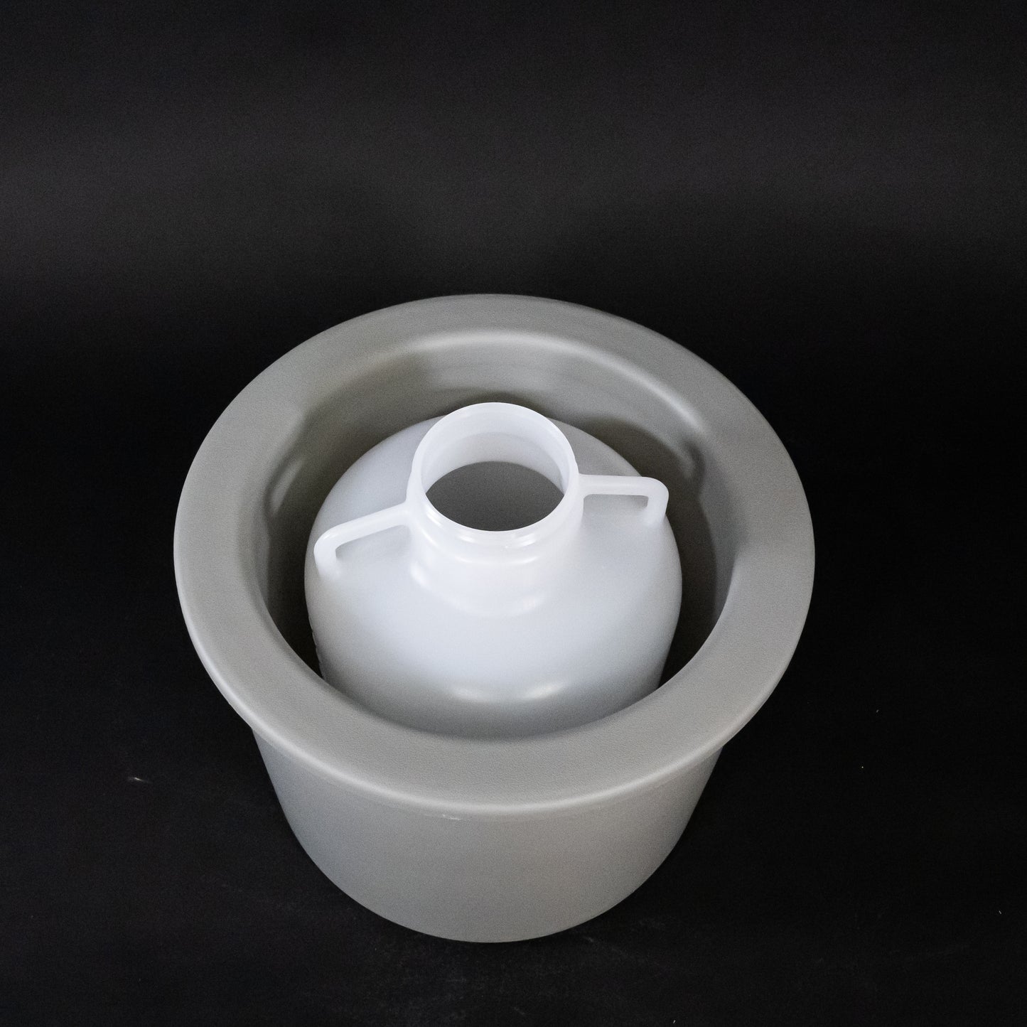 A gray bucket containing a white plastic jug, illustrating a practical storage solution.