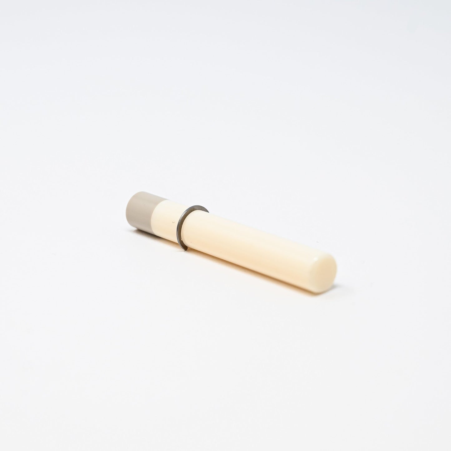 A compact white tube equipped with a ring for enhanced usability and convenience.