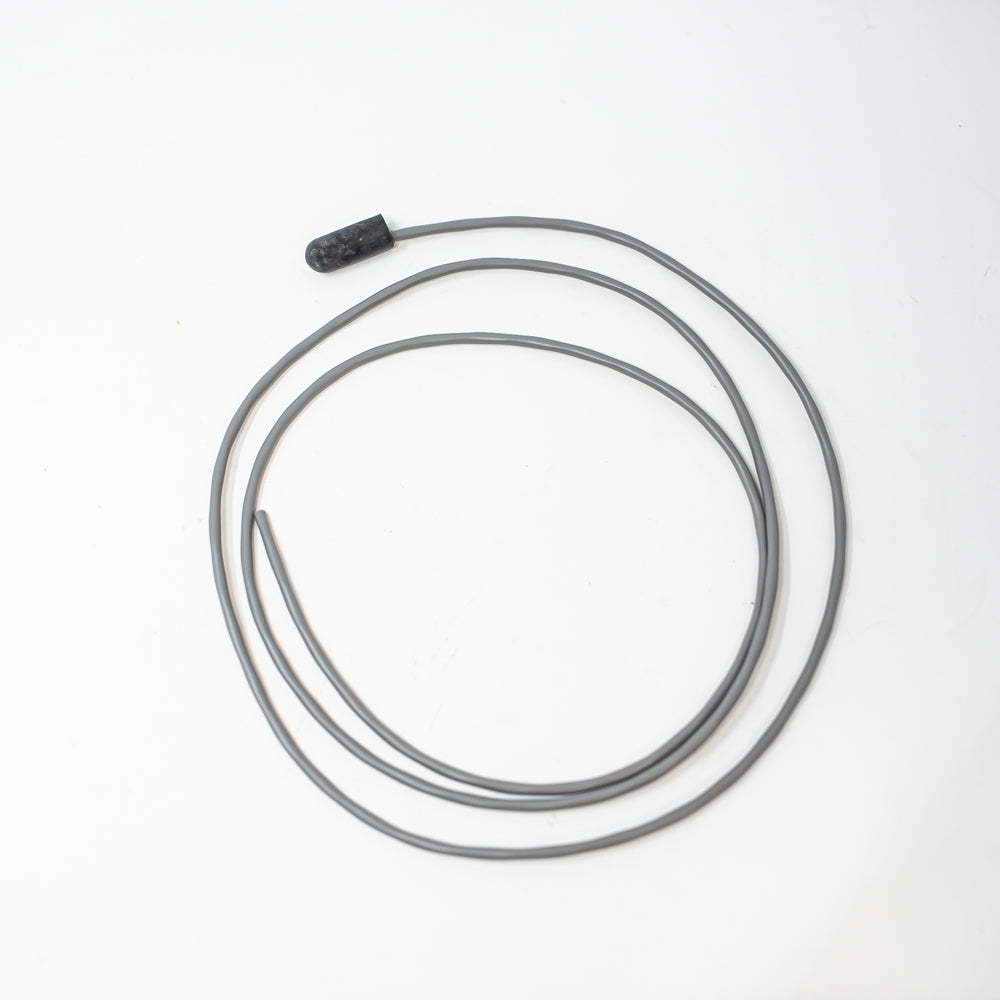 A grey cable with a black sensor lies on a white surface, showcasing a simple yet functional design.