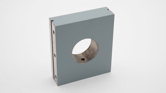 A grey rectangular object with a threaded hole