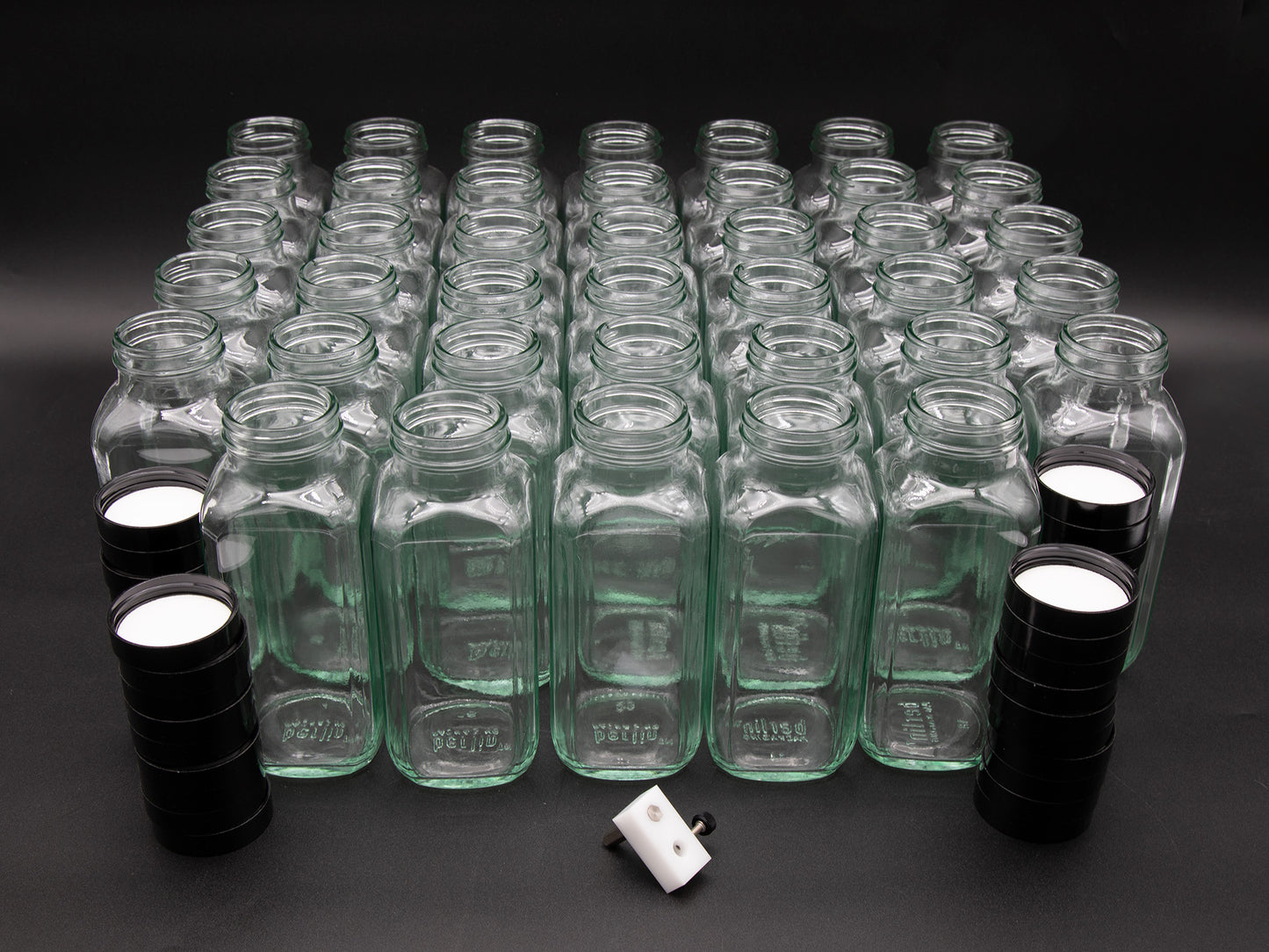 A large collection of empty glass bottles arranged against a solid black background, creating a striking visual contrast.