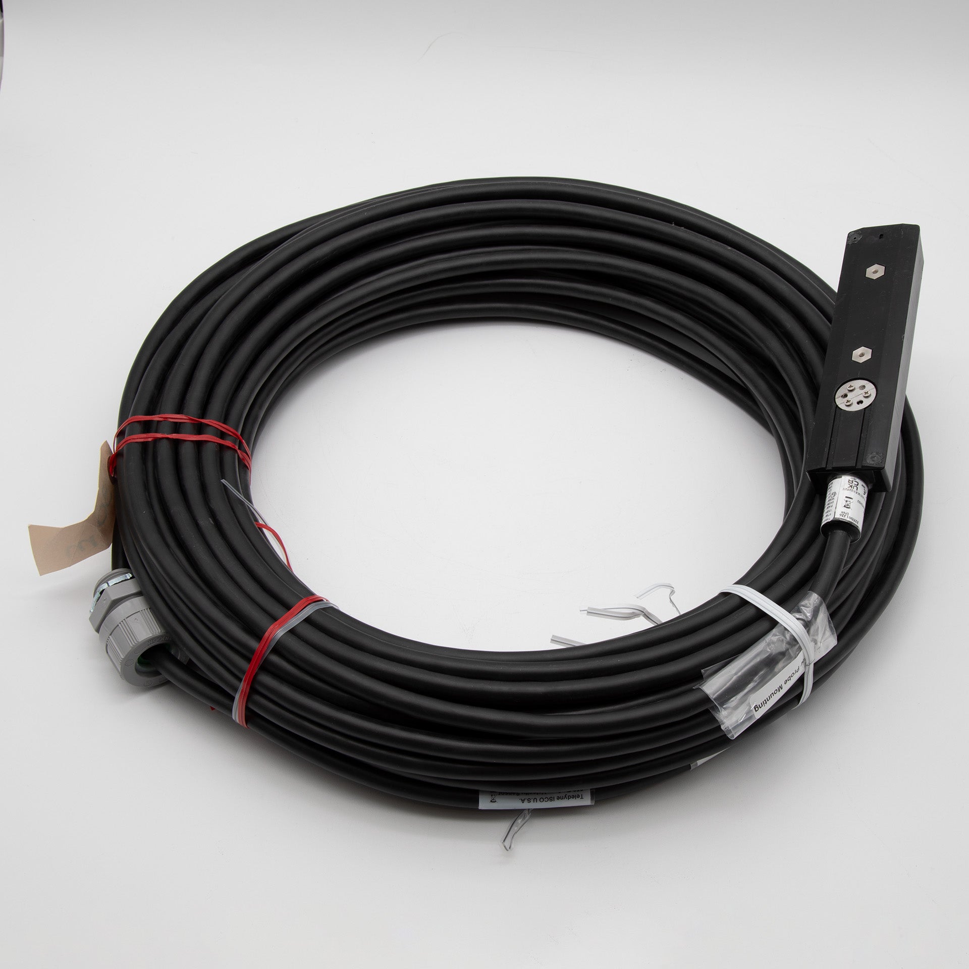 A black cable with a rectangular shaped sensor attached, positioned on a plain background.