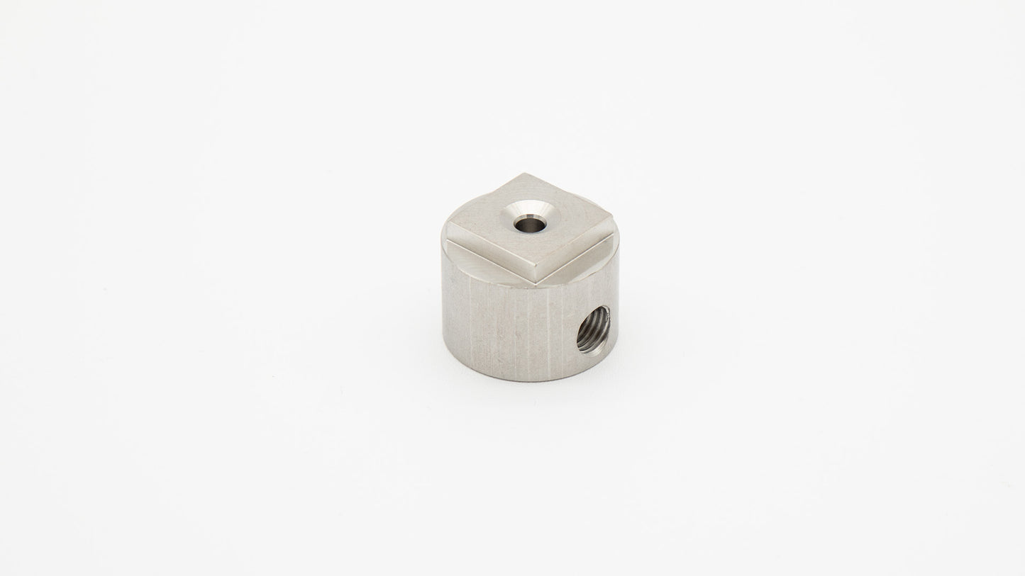 Cylindrical piece with threaded ports and square top.