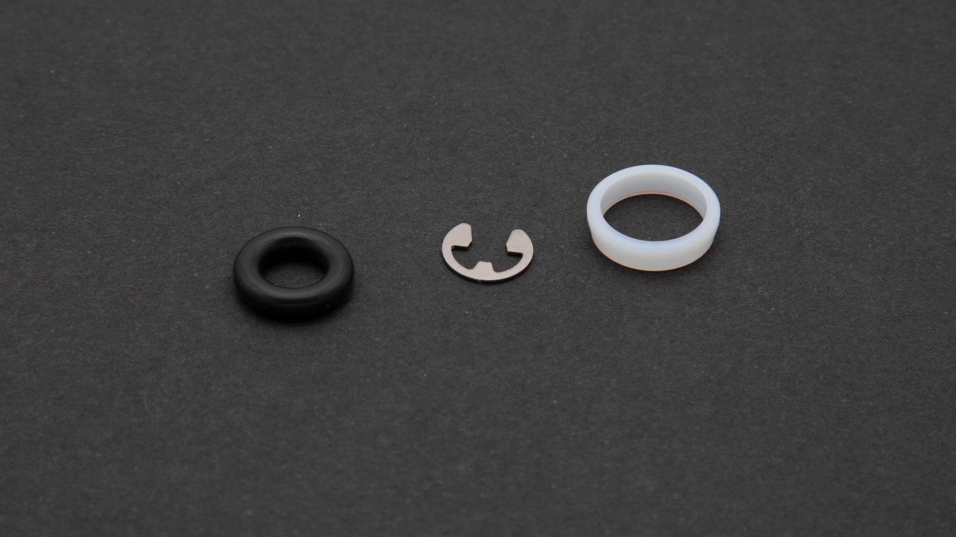 A black ring alongside a white ring, showcasing a stainless steel retaining ring.