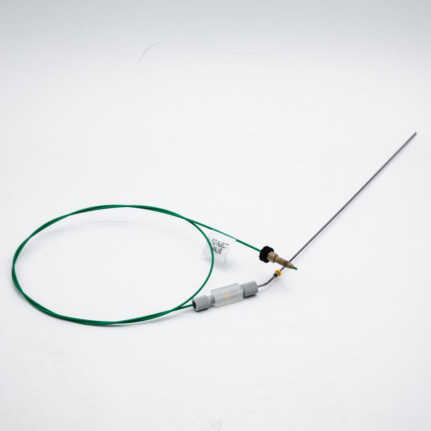 Device with green cable and needle on a white background