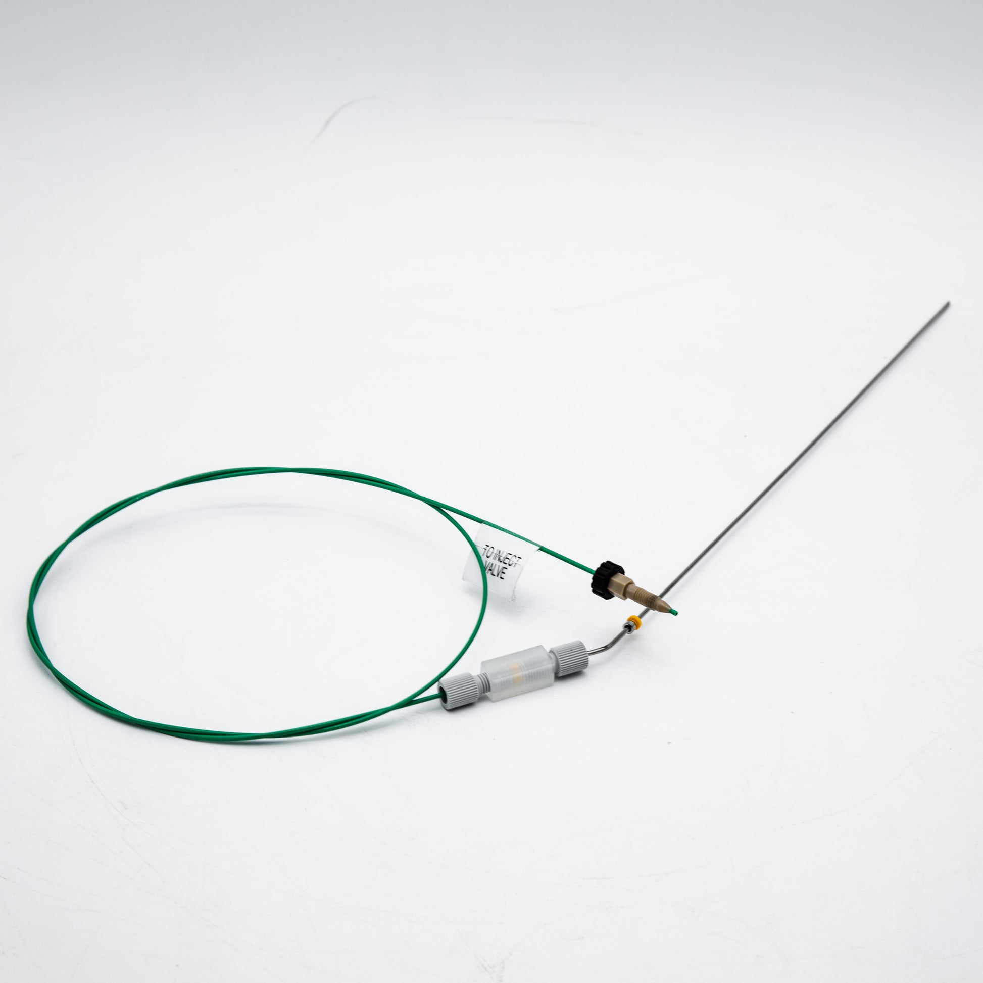 Device with green cable and needle on a white background