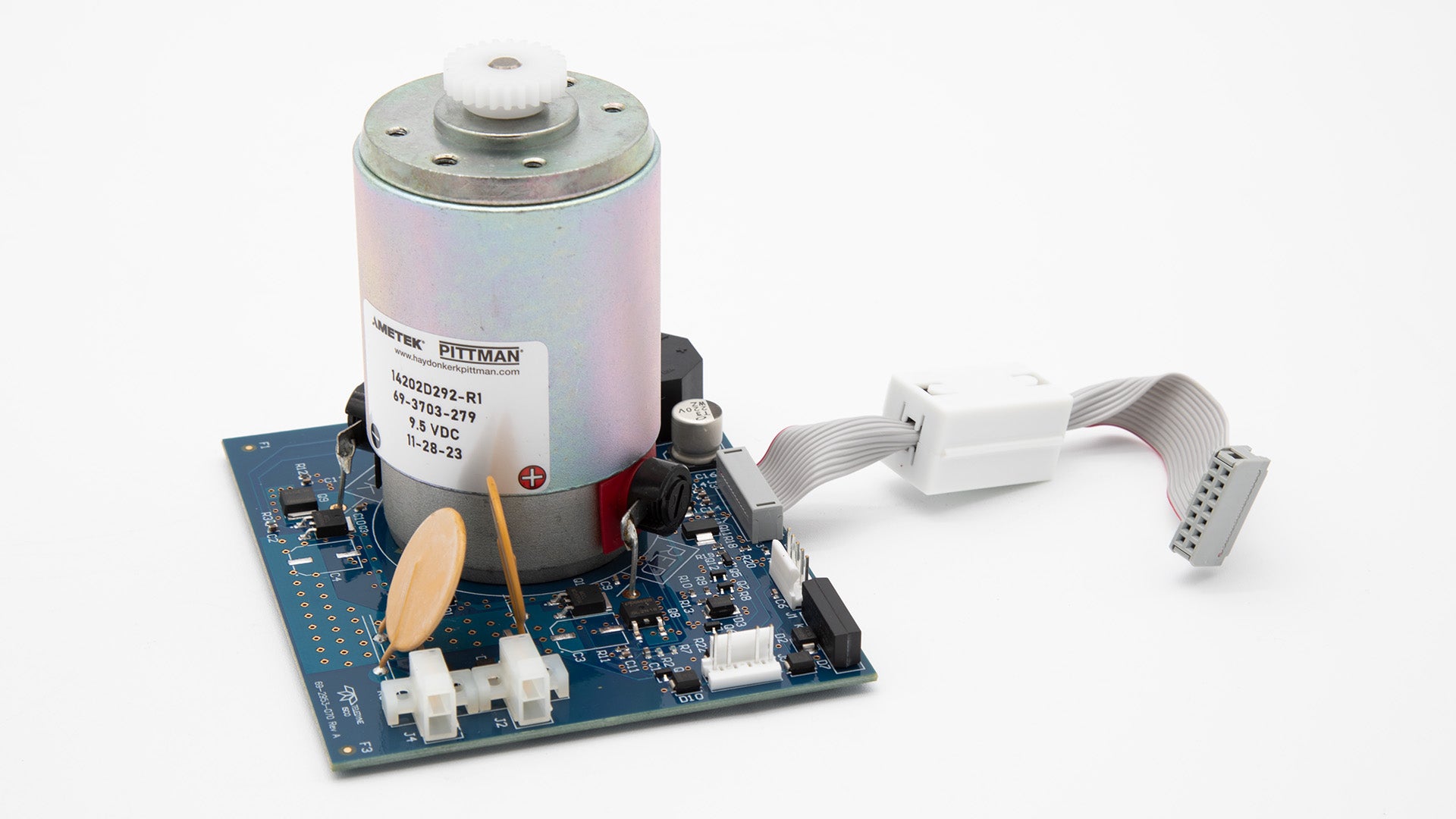 A motor and a circuit board placed on a clean white surface, showcasing their intricate designs and components.
