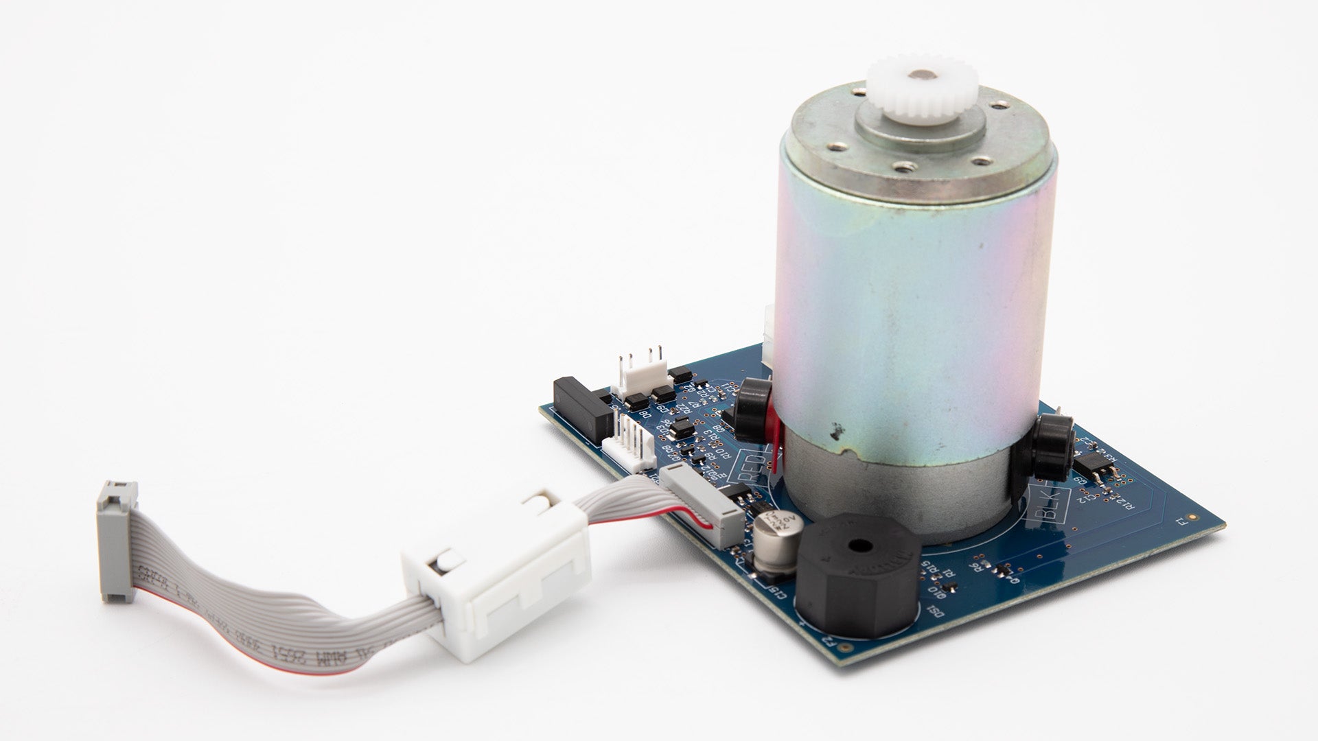 A motor and a circuit board placed on a clean white surface, showcasing their intricate designs and components.
