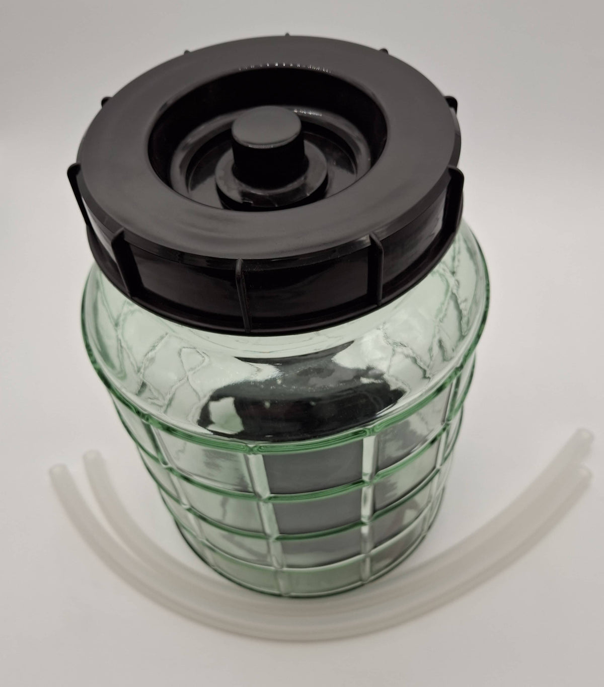A clear glass jar with a black screw-on lid and a black filter insert, shown on a white background with two translucent plastic tubes.