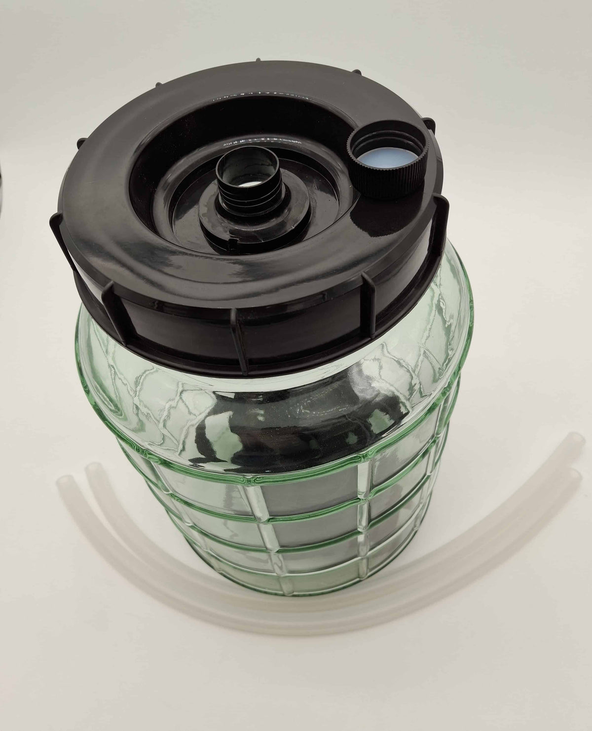 A clear plastic reservoir bottle with a black screw-on cap and a green grid-like reinforcing ring, shown on a white background with two clear tubes.