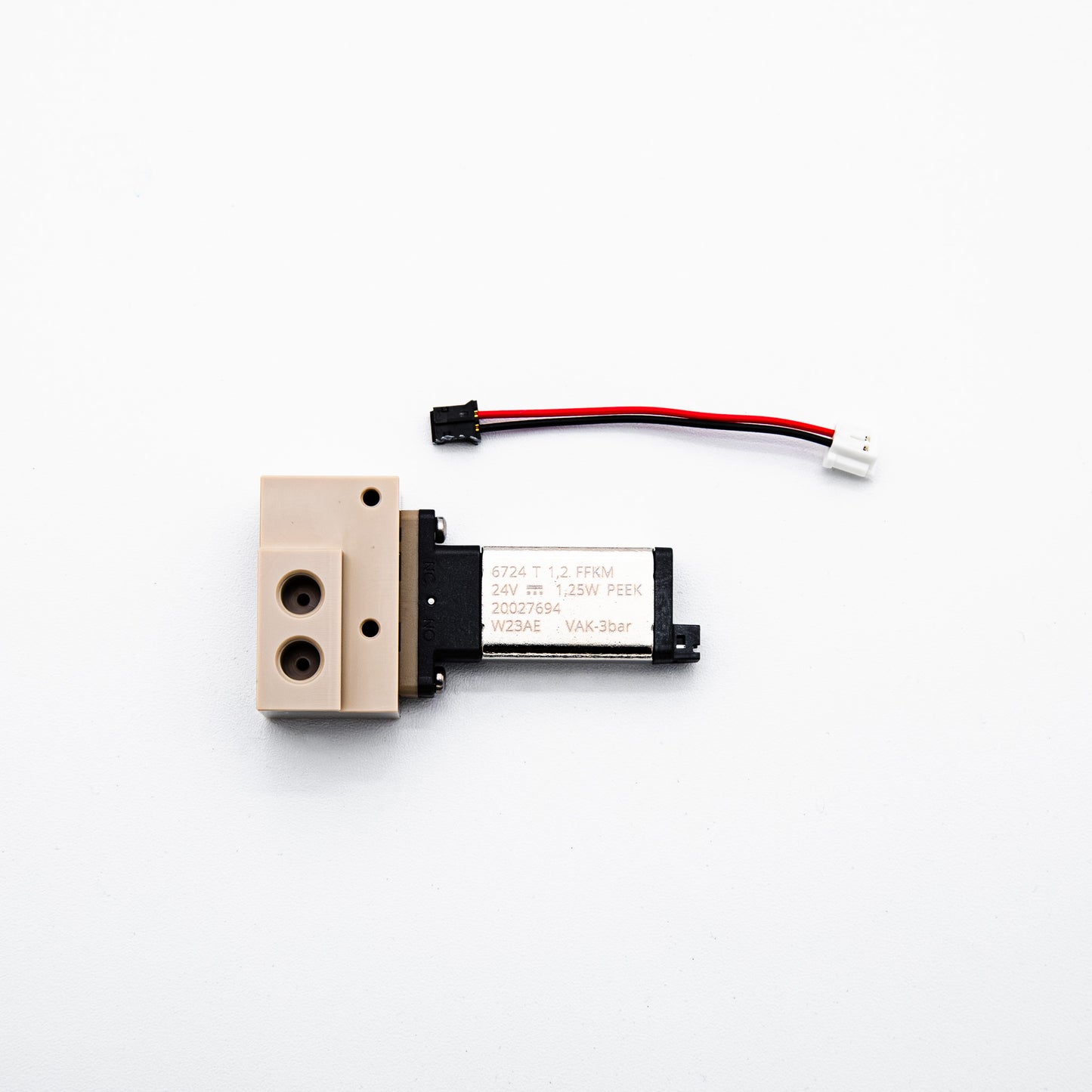 A small industrial solenoid valve with a beige plastic body and a black electrical connector wire, photographed on a clean white background.