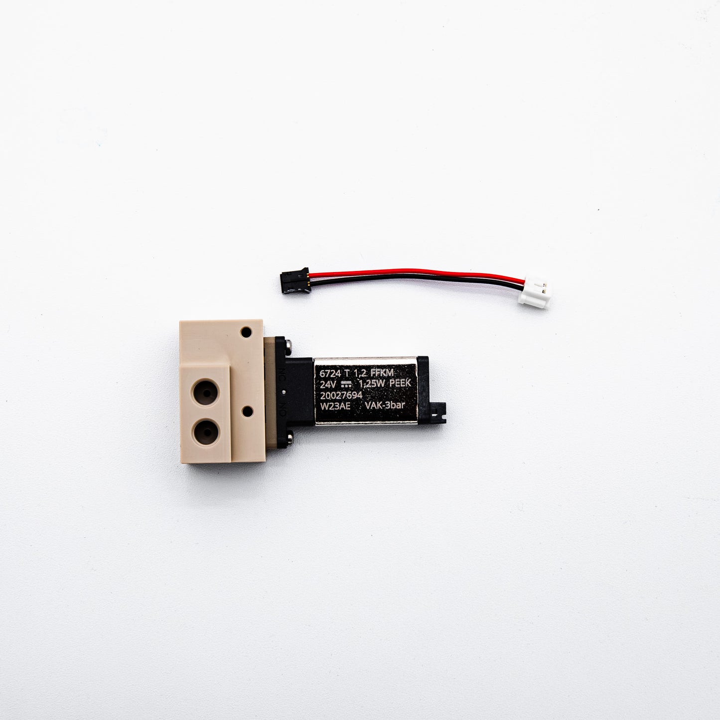 A small electronic solenoid valve component with a beige plastic body, black coil, and a red-and-black wire connector, photographed on a plain white background.