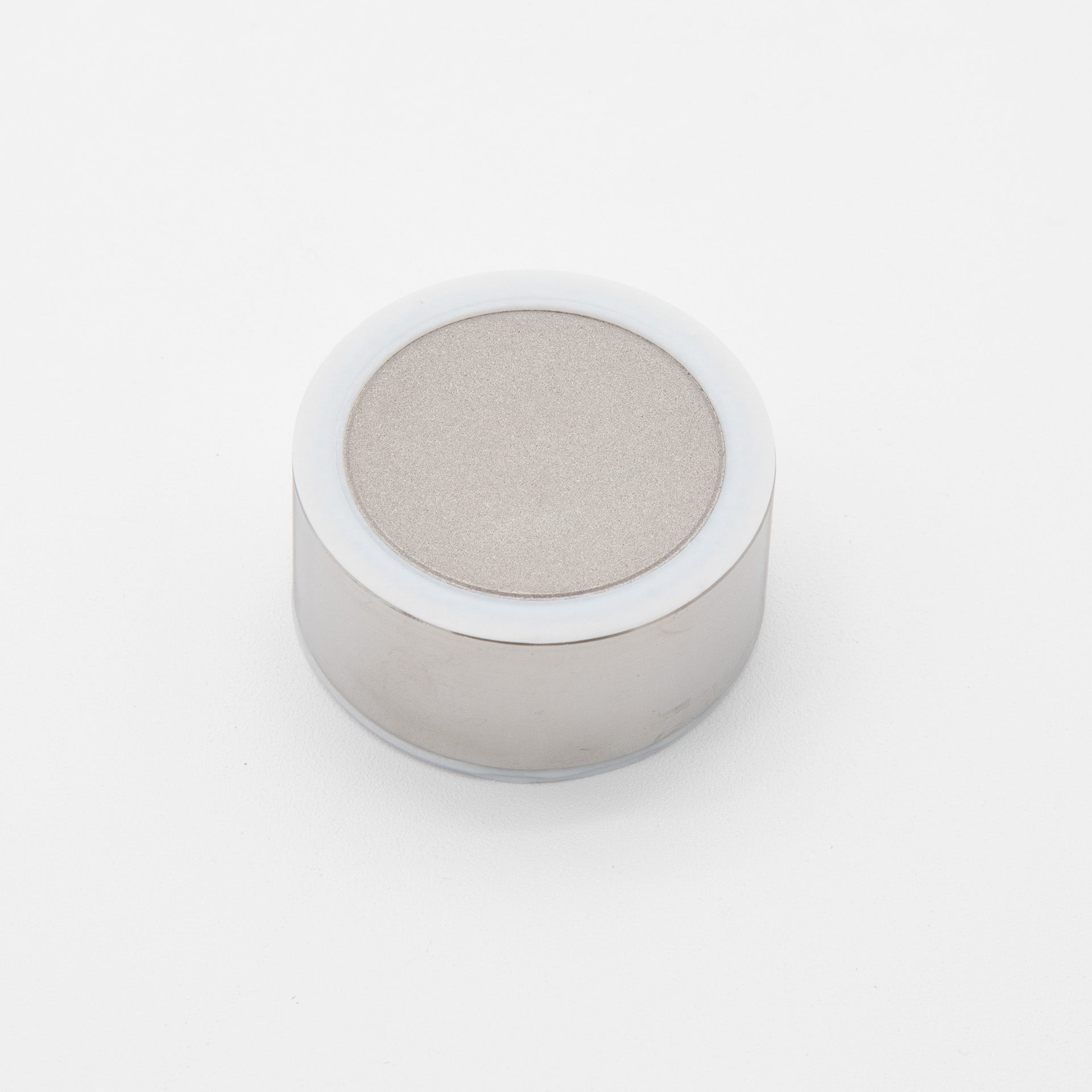 A white metal object featuring a smooth, round top, reflecting light in a minimalist setting.