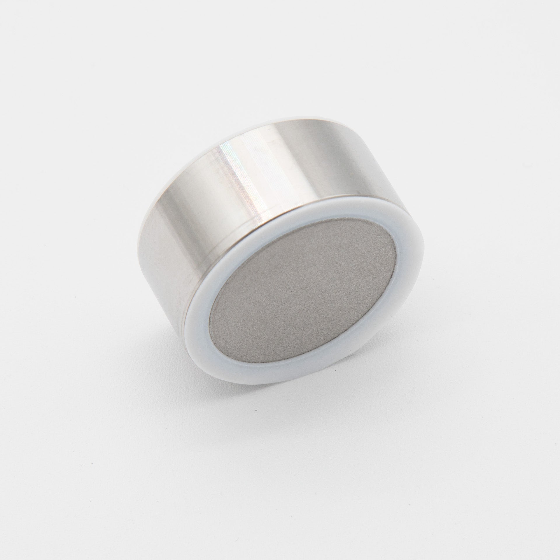 A cylindrical metal object featuring a smooth, round top, reflecting light in a minimalist setting.