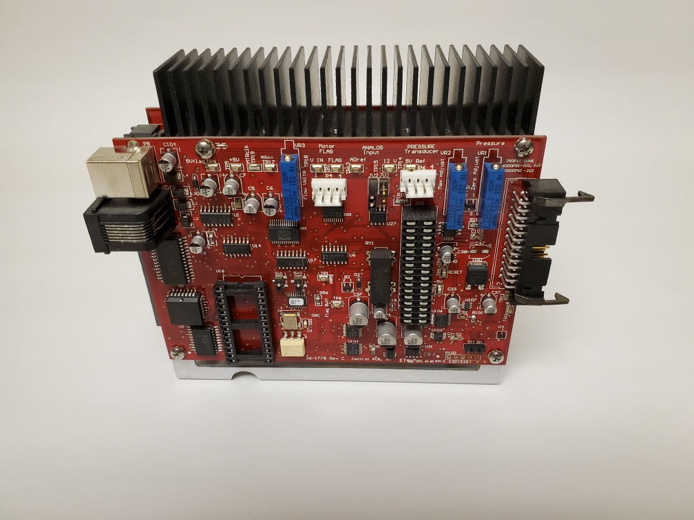 A red electronic circuit board featuring various blue and black components arranged across its surface.
