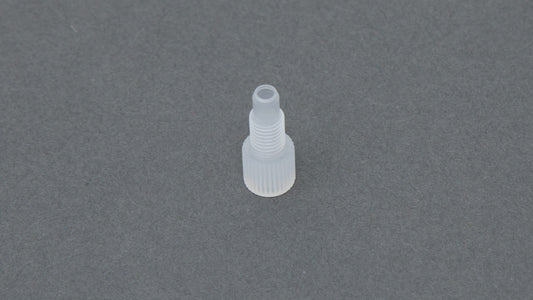 A clear plastic nut resting on a smooth gray surface, showcasing its simple and functional design.