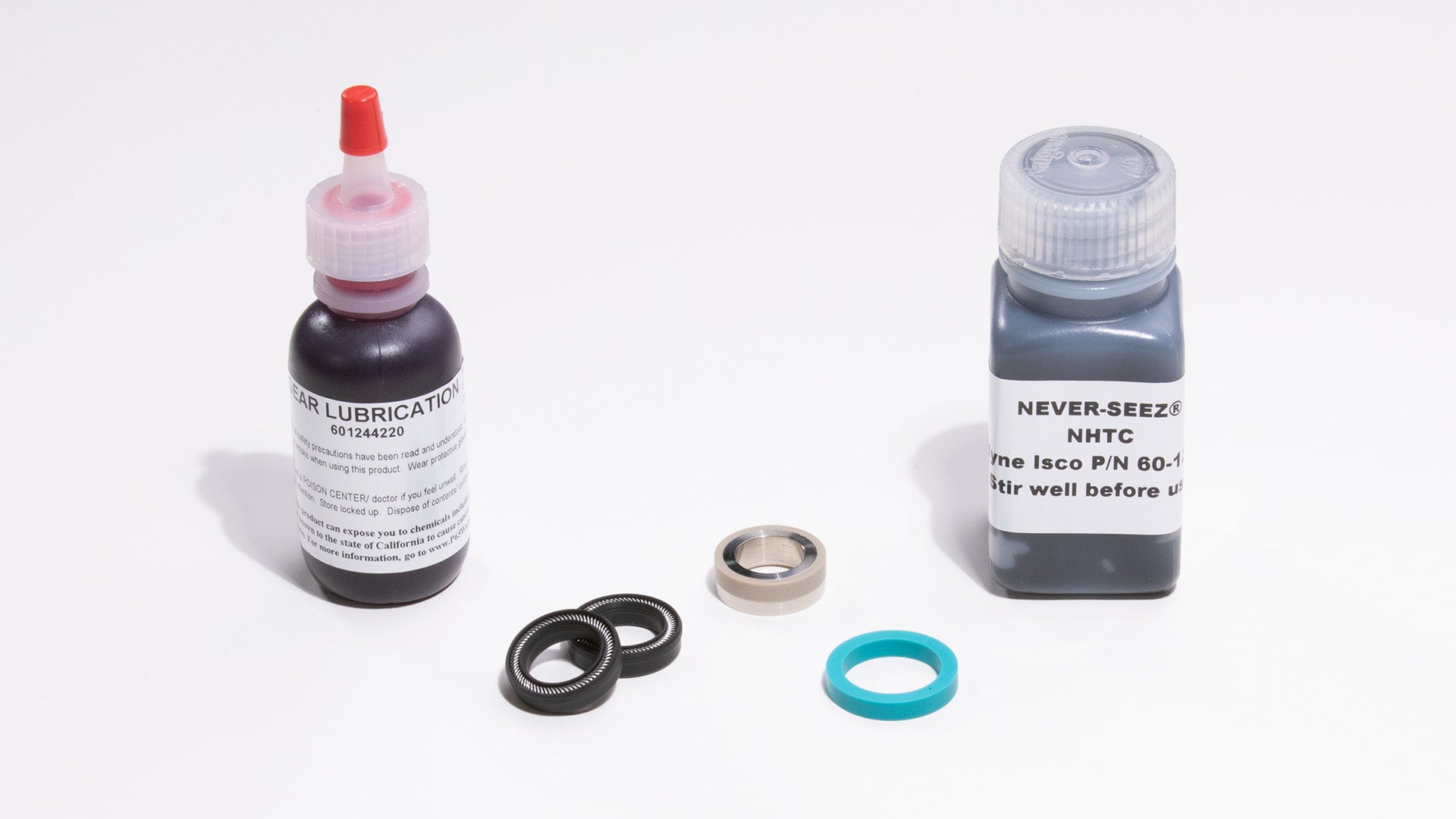 Two bottles of lubricant and some seals, displayed on a smooth surface.