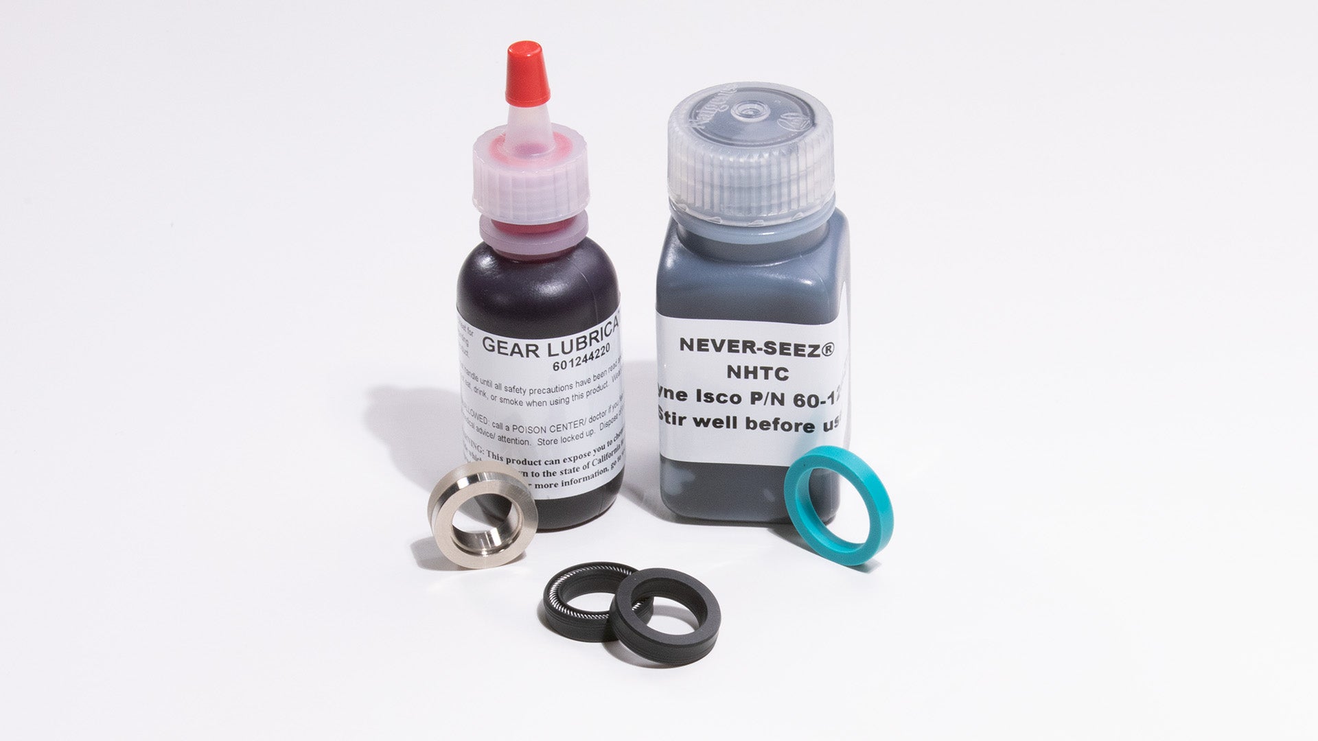 Two bottles of lubricant and some seals, displayed on a smooth surface.