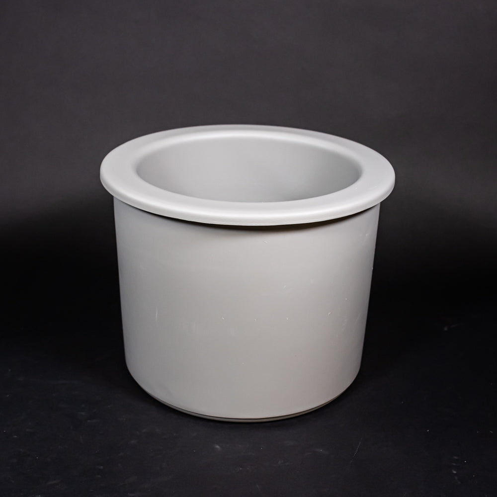 A grey plastic tub set against a dark black surface, highlighting its design and form.