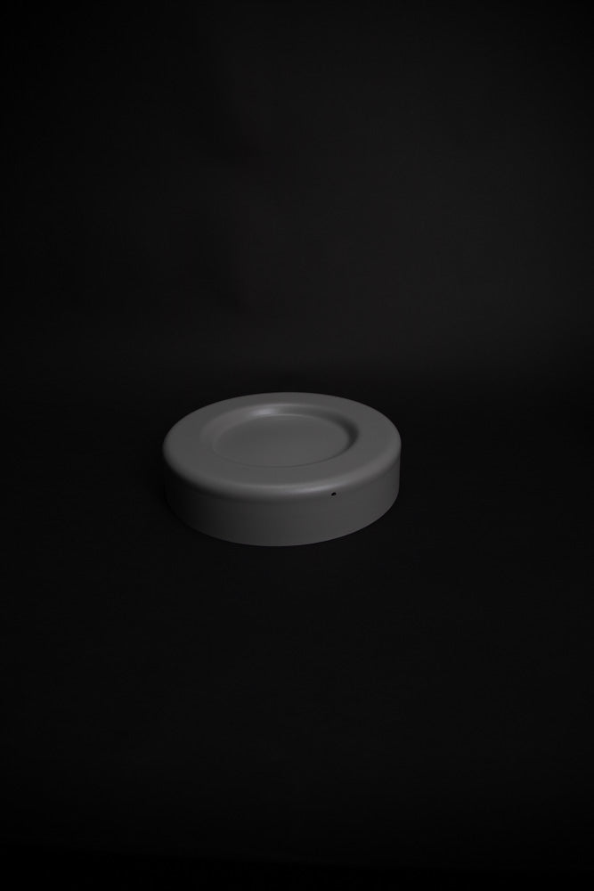 Round plastic tray with shallow recess for bottle placement