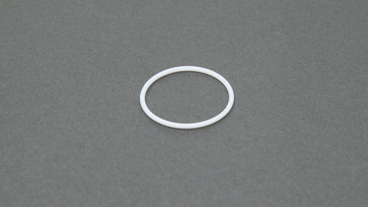 A white ring rests on a smooth gray surface, creating a striking contrast between the two colors.