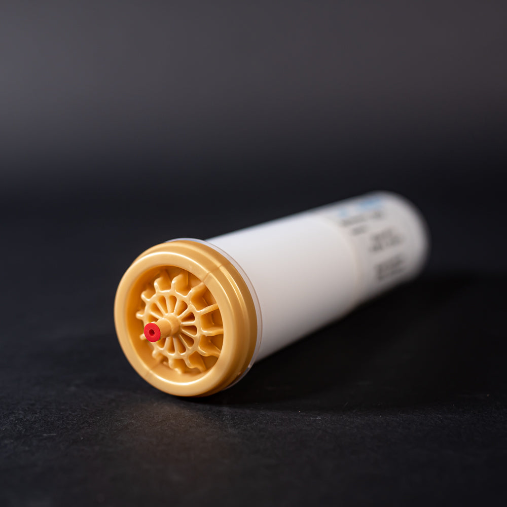 A small white tube with gold and red caps displayed on a black background, creating a striking visual contrast between the two elements.